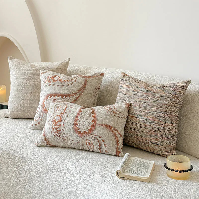 American-style jacquard pillow cover with paisley and flower pattern in amber colour, shown on a sofa.