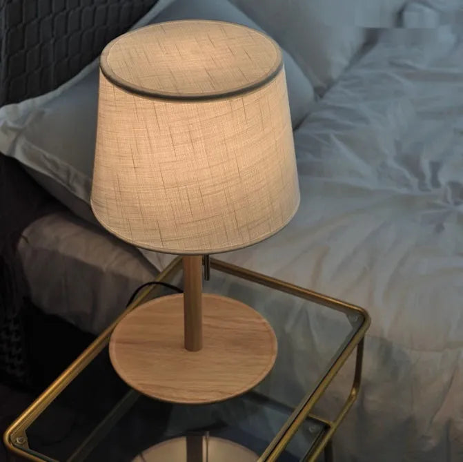 Walnut coloured solid wood bedside table lamp with a white cloth lampshade.