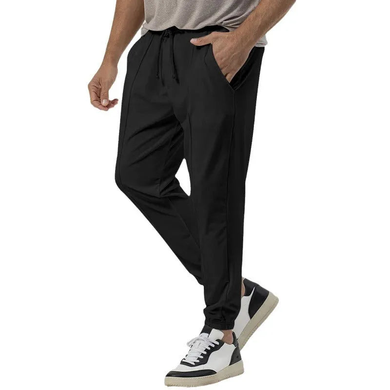 Man wearing gray straight-leg casual track sweatpants with a tapered fit and elastic waistband.