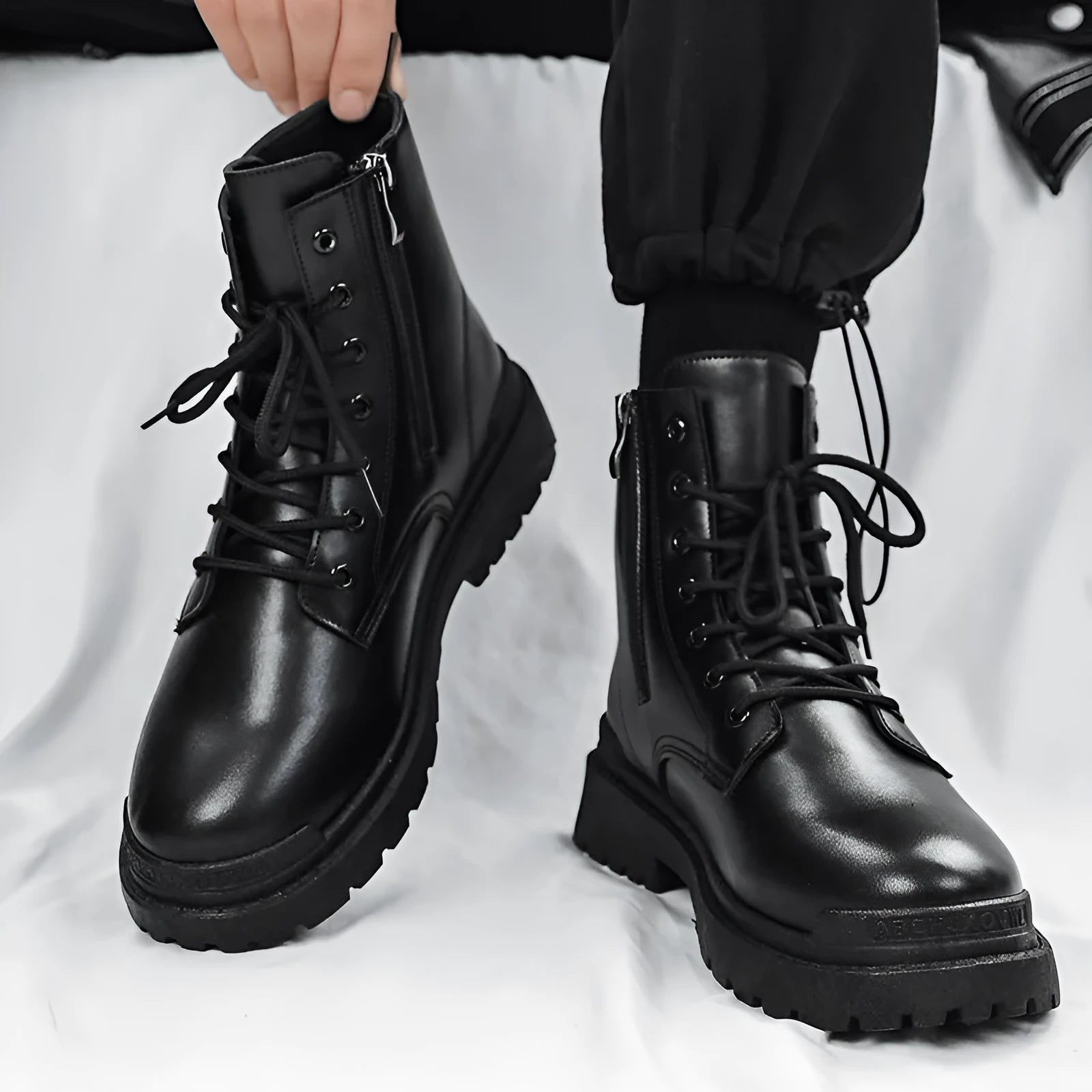 Men's mid-top black waterproof leather boots with non-slip rubber sole on flat surface