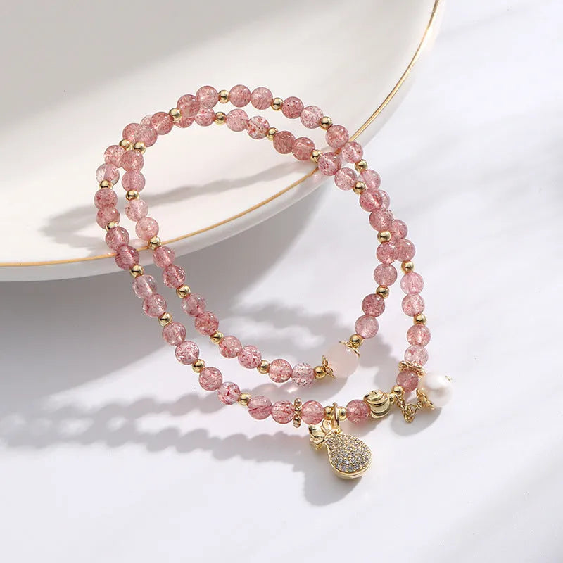 Geometric strawberry quartz crystal bracelet for women on a wrist.