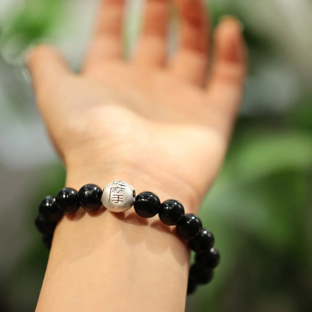 Black agate bracelet with 10mm beads and a sterling silver clasp on a wrist.