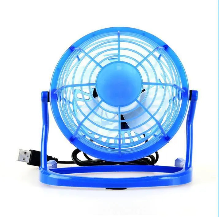 Mini black USB desk fan with adjustable head on a wooden desk next to a laptop.