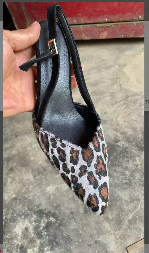 Women's leopard print suede sandals with a pointed toe and high heel on a neutral background.