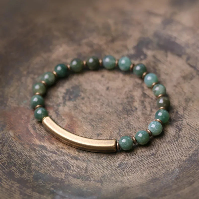 Layered retro ethnic bracelet with natural stone beads and antique brass details on a wrist.