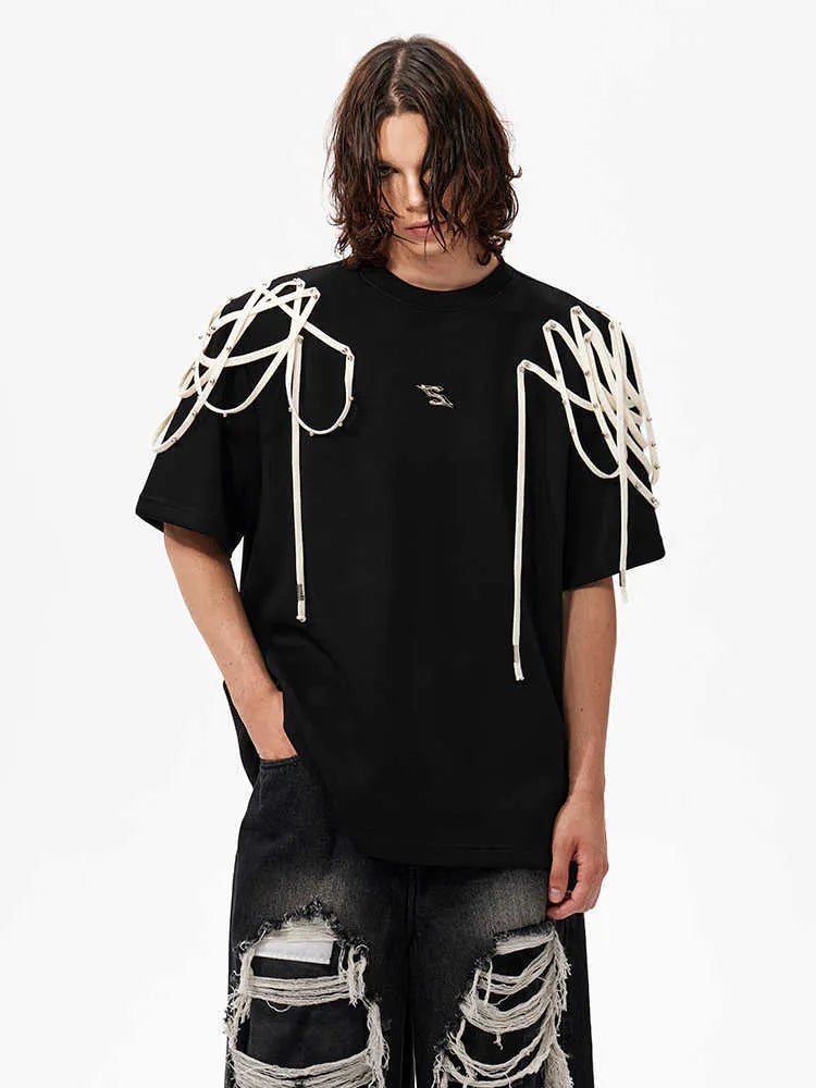 Black loose-fit short-sleeve t-shirt with padded shoulders featuring a decorative rivet and ribbon detail.