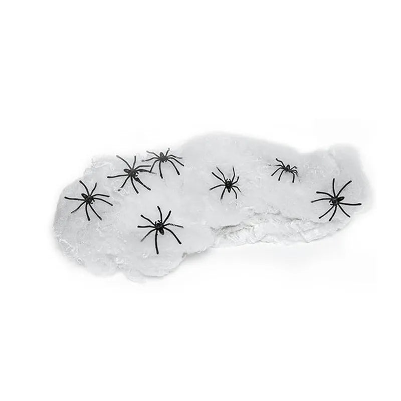 White cotton spider web Halloween decoration draped over a branch with plastic spiders.