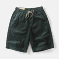 Men's khaki retro-style cargo shorts with a straight leg on a summer streetwear background.