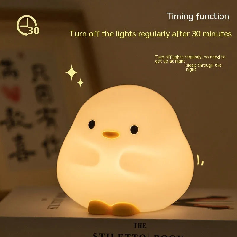 Cute duck-shaped silicone LED night lamp on a bedside table with warm light
