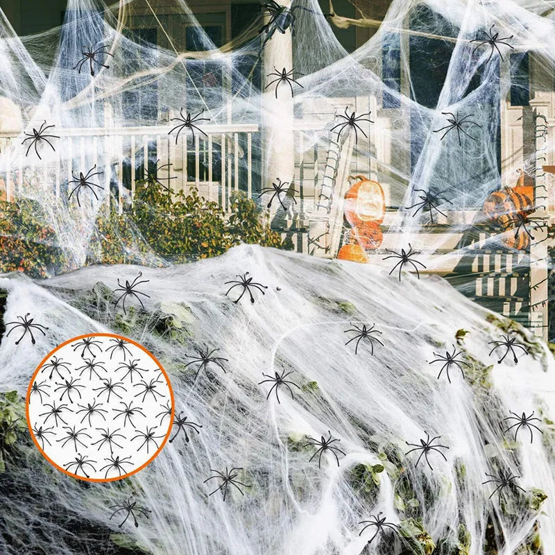 White cotton spider web Halloween decoration draped over a branch with plastic spiders.