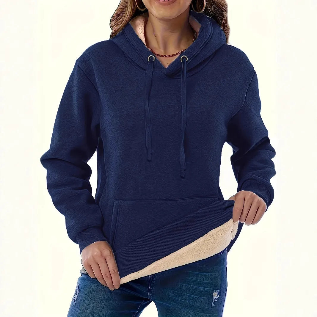 A woman wearing a thick, grey, loose-fit hooded sweatshirt with a 3D pattern and front pockets.