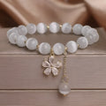 White cat's eye crystal bracelet with flower tassel charm and safety buckle closure