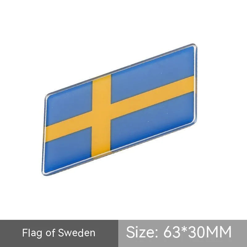 Aluminium parallelogram car sticker showing a national flag design, measuring 6.3 by 3 centimetres.