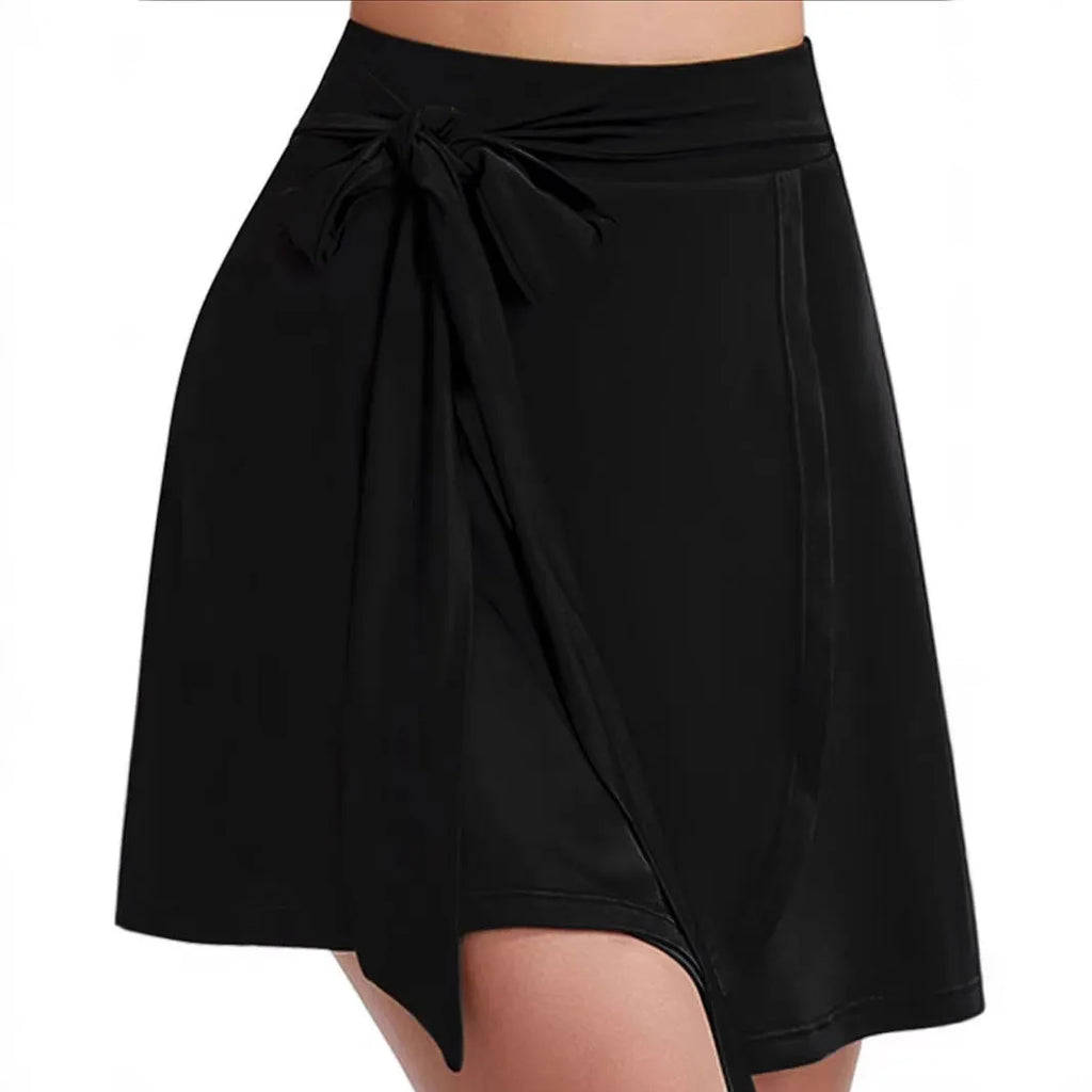 Black thigh-length sports skirt with high waist and built-in shorts, featuring shoulder strap detail and culotte silhouette