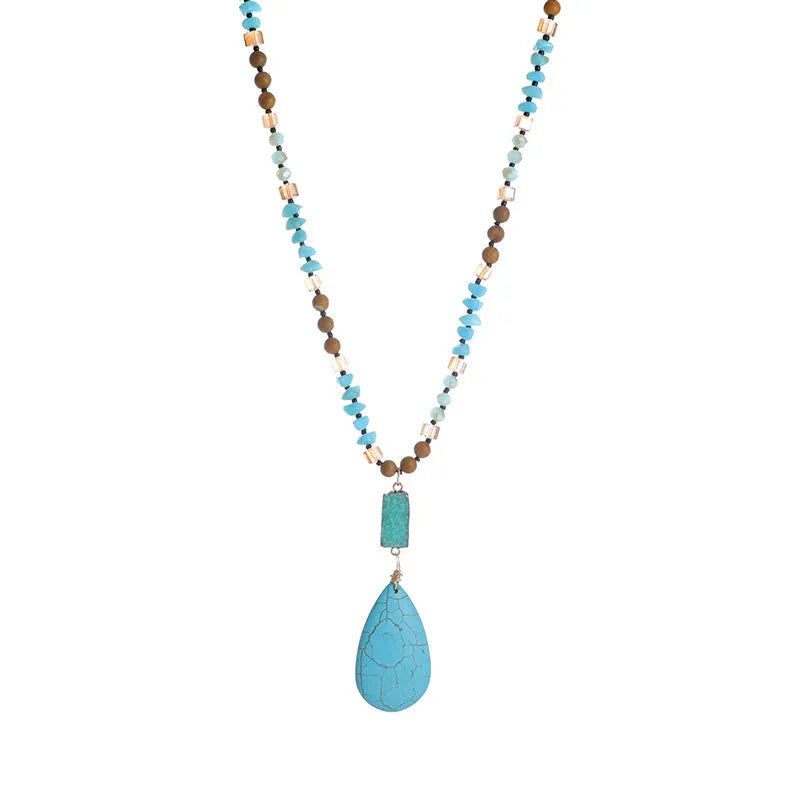 Close-up of a large turquoise blue heart-shaped water drop pendant necklace on a ball bead chain.