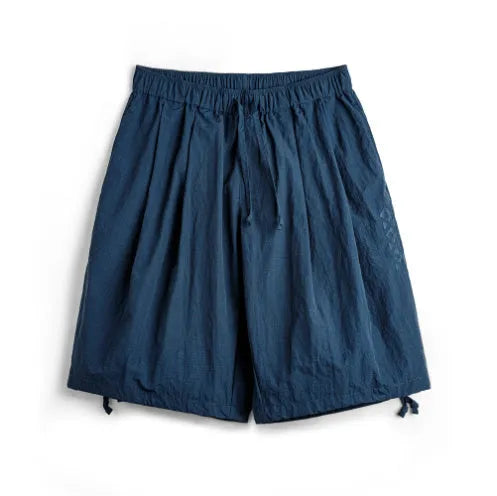 Men's loose fit Prussian blue nylon beach shorts with embroidery on a white background.