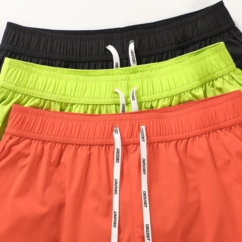Man wearing loose orange red polyester beach shorts with elasticated waistband.