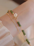 Natural olivine gemstone bracelet with double layers and twin Bells of Ireland charms on a wrist.