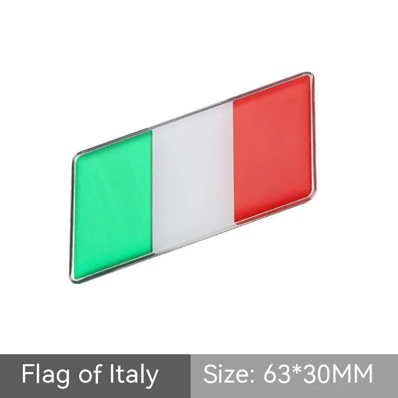 Aluminium parallelogram car sticker showing a national flag design, measuring 6.3 by 3 centimetres.