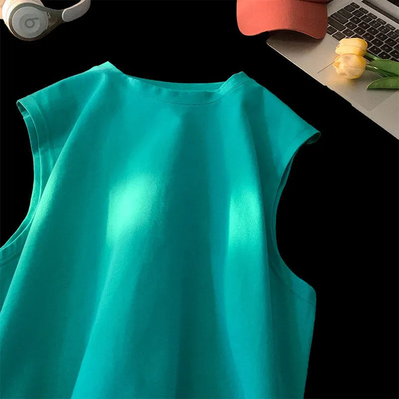 Men's loose-fitting solid colour cotton tank top on a hanger, shown in a light colour.