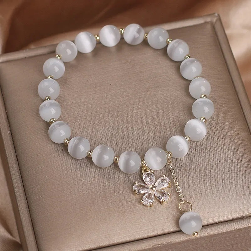 White cat's eye crystal bracelet with flower tassel charm and safety buckle closure