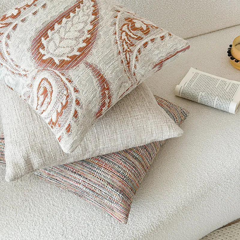 American-style jacquard pillow cover with paisley and flower pattern in amber colour, shown on a sofa.