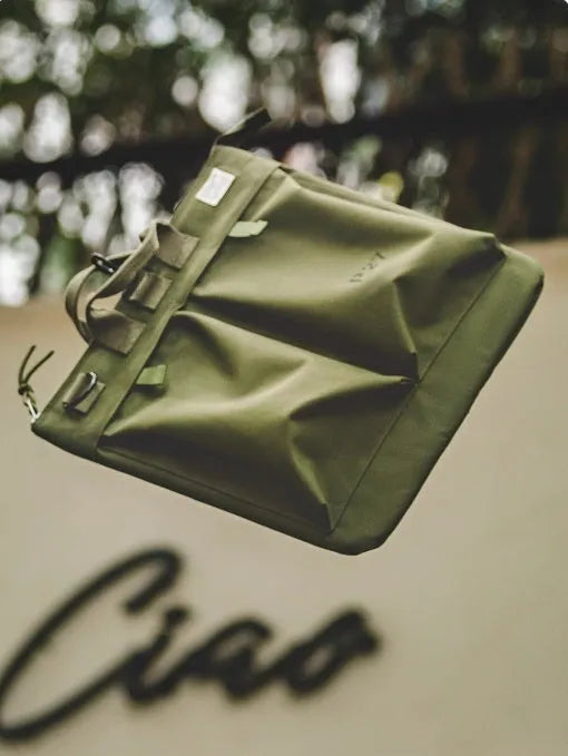 Medium canvas crossbody messenger bag in military green showing laptop compartment and shoulder strap