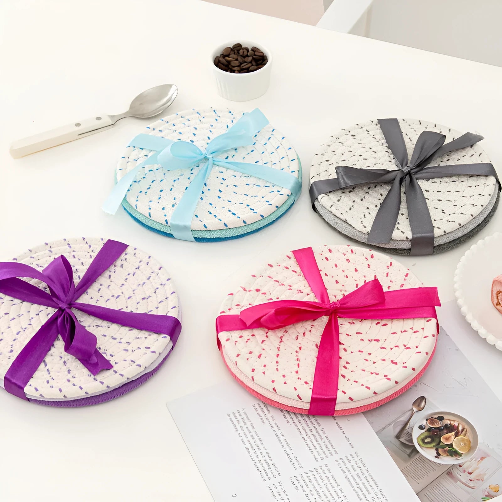 Set of three round grey cotton cord coasters on a wooden table.