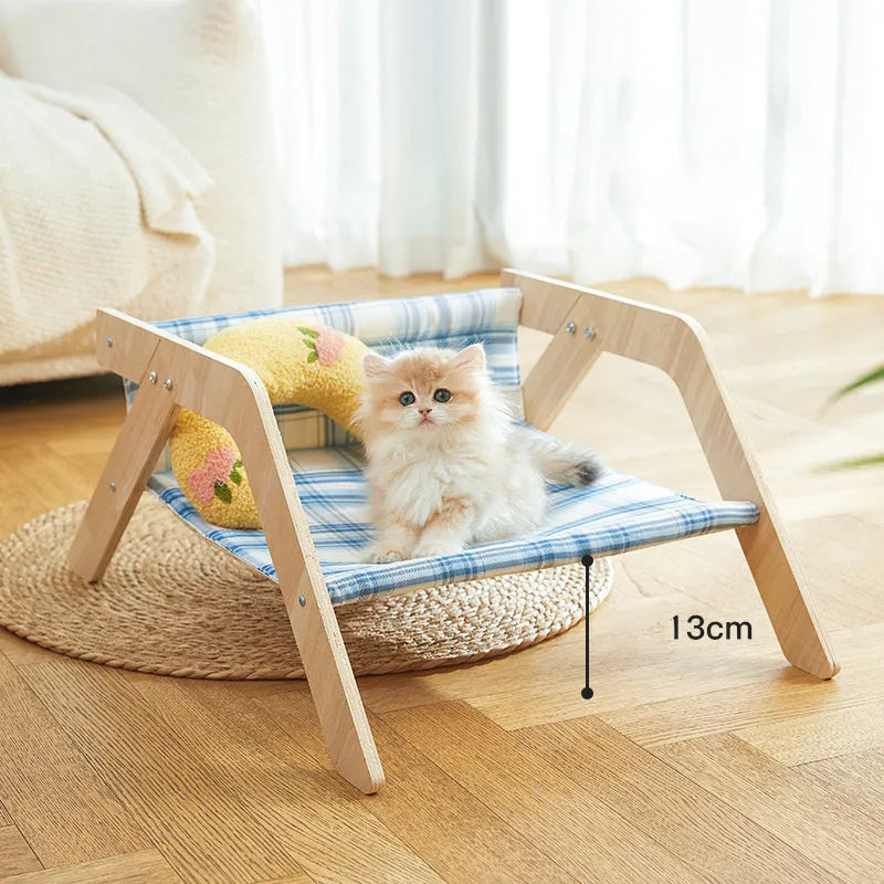 Blue elevated cat hammock bed with wooden beach chair frame on a white floor.