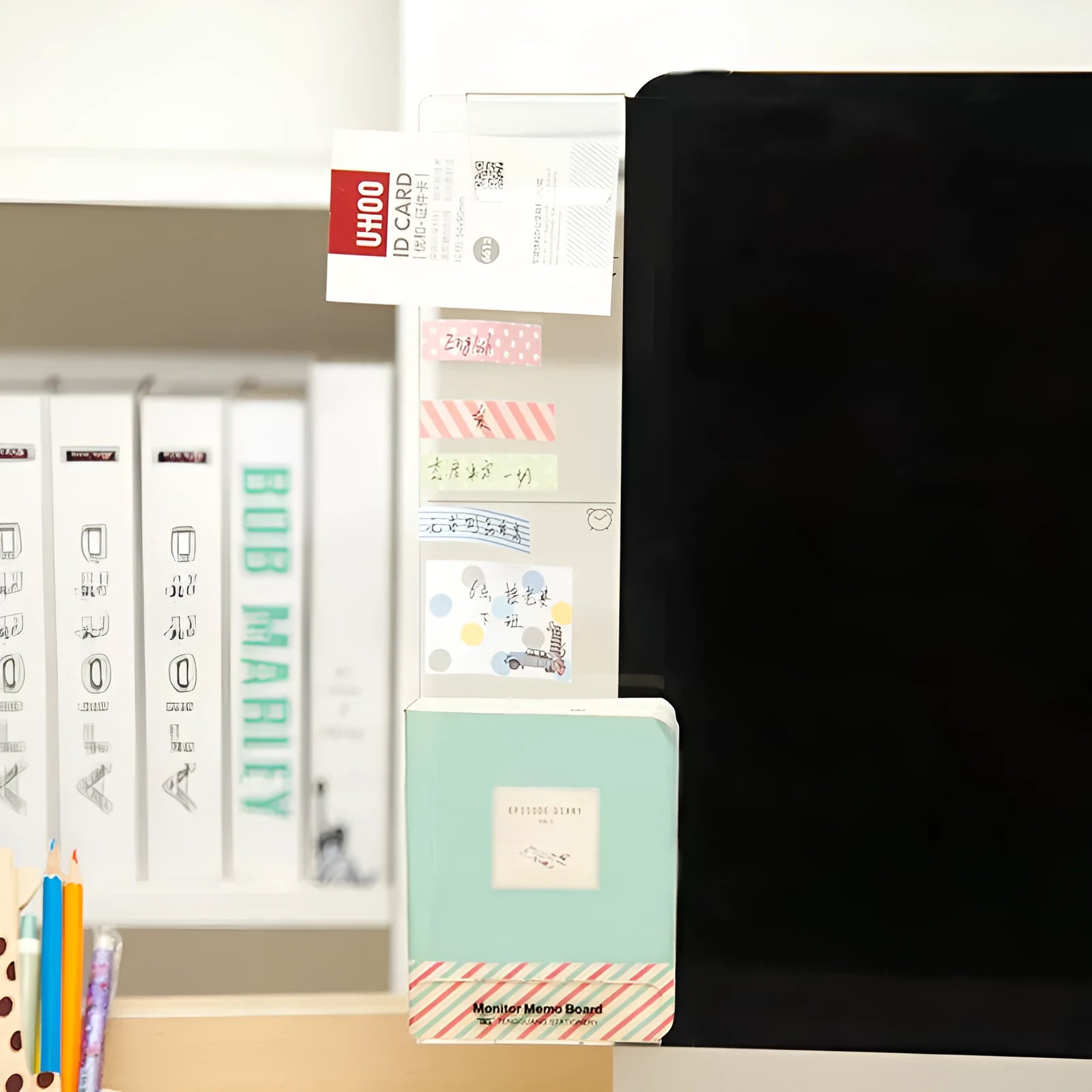 Acrylic monitor message memo board attached to monitor with wall suction, holding a post-it note