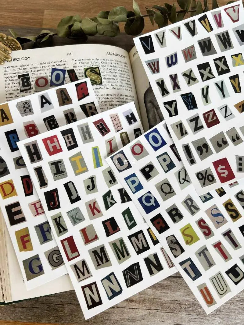 Set of printed cute-style stickers showing English letters A, B, C, D, E, numbers, symbols, and weekly words on a sheet.