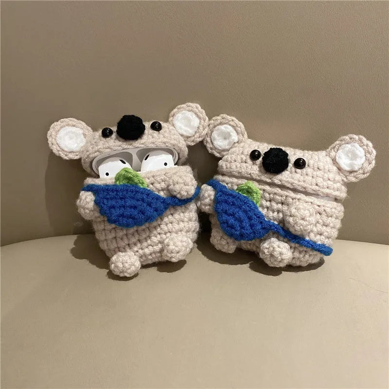 Handmade knitted koala bear backpack cover for Apple Airpods case on a table.