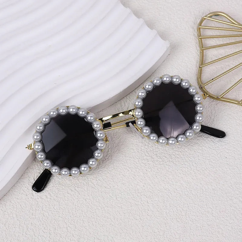 Pearl-rimmed round sunglasses for cats and dogs in multiple colours on a pink background.