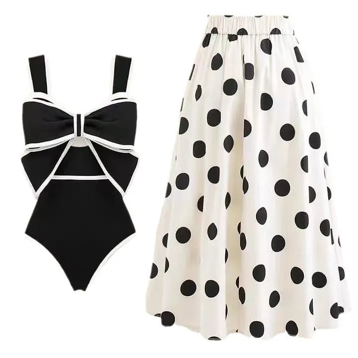 A black one-piece swimsuit for women with a white detachable skirt and a decorative bow at the front.