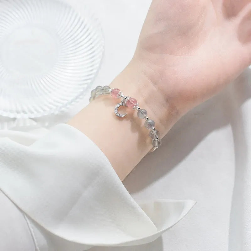 Adjustable natural moonstone bracelet with crescent moon charm on a wrist, showing extension chain.