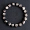 Natural obsidian crater ball bracelet with meteorite-like texture in silver stone or gold finish.