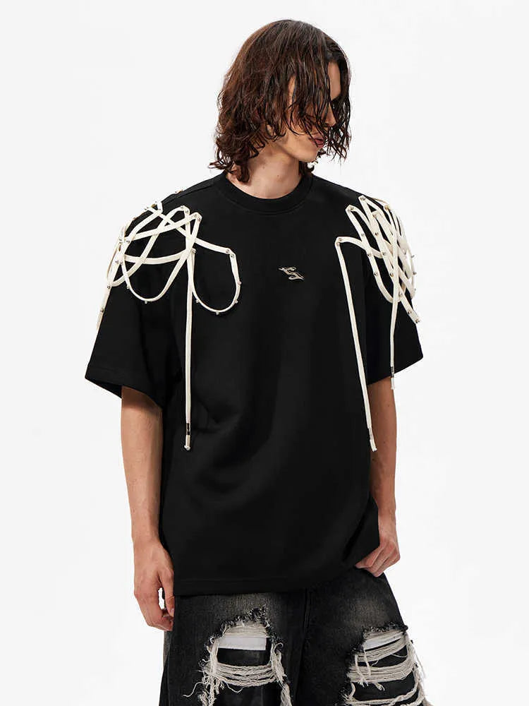 Black loose-fit short-sleeve t-shirt with padded shoulders featuring a decorative rivet and ribbon detail.