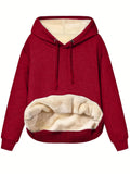 A woman wearing a thick, grey, loose-fit hooded sweatshirt with a 3D pattern and front pockets.