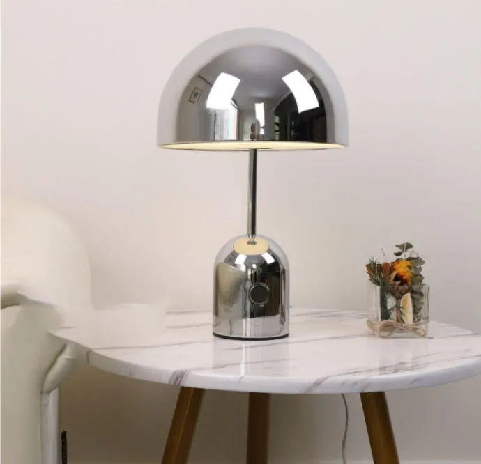 Mushroom-shaped metal table lamp in rose gold finish on wooden surface
