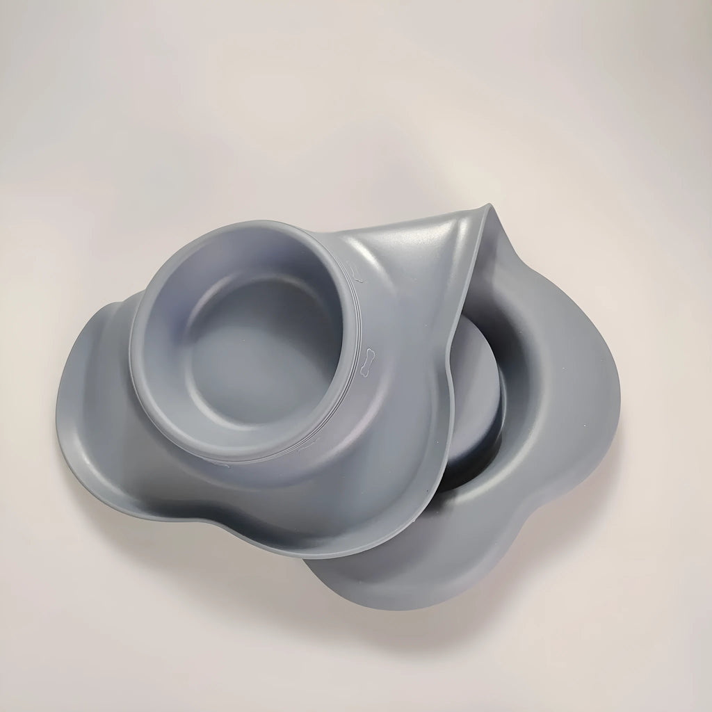 Large silicone double dog bowl in blue with two compartments for food and water on a kitchen floor.