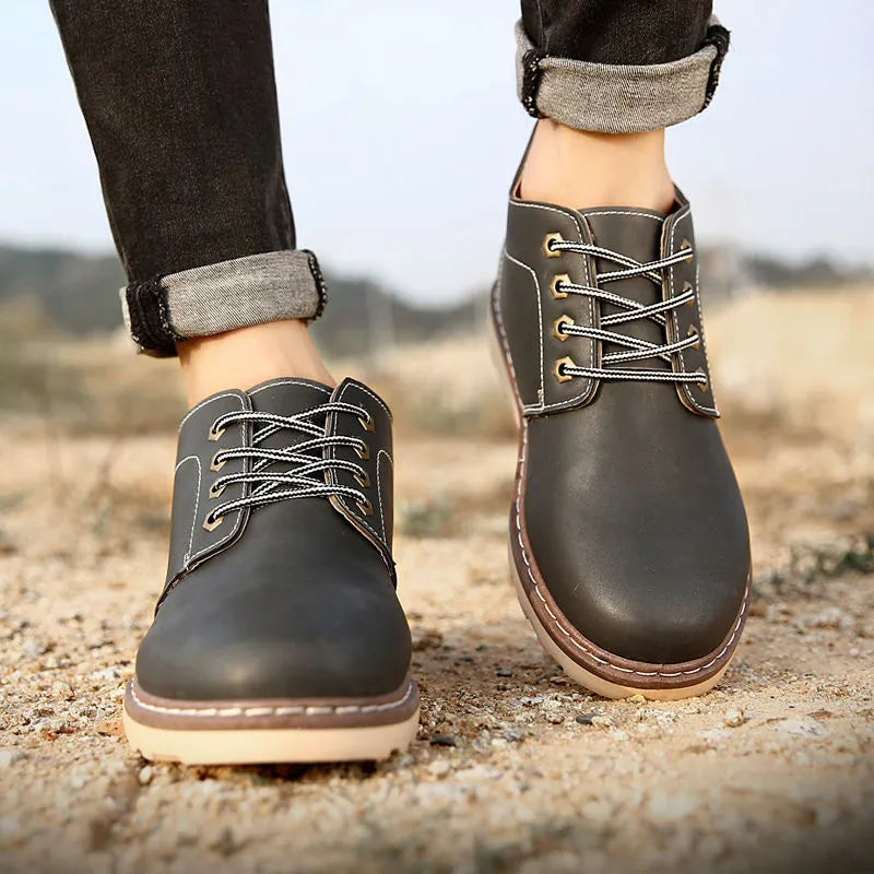 Men's mid-top black waterproof leather boots with non-slip rubber sole on flat surface