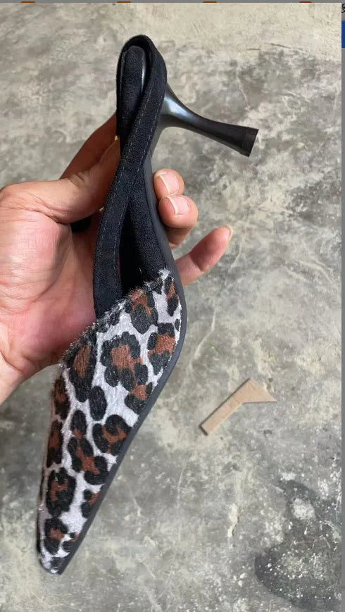 Women's leopard print suede sandals with a pointed toe and high heel on a neutral background.