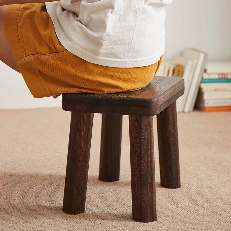 Solid wood shoe changing stool with a distressed rustic finish and sturdy bracket legs.