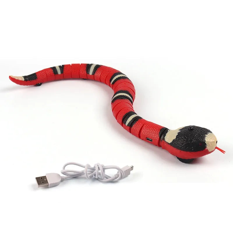 Smart sensing interactive electronic snake cat toy on a floor, showing segmented plastic body and USB charging port.
