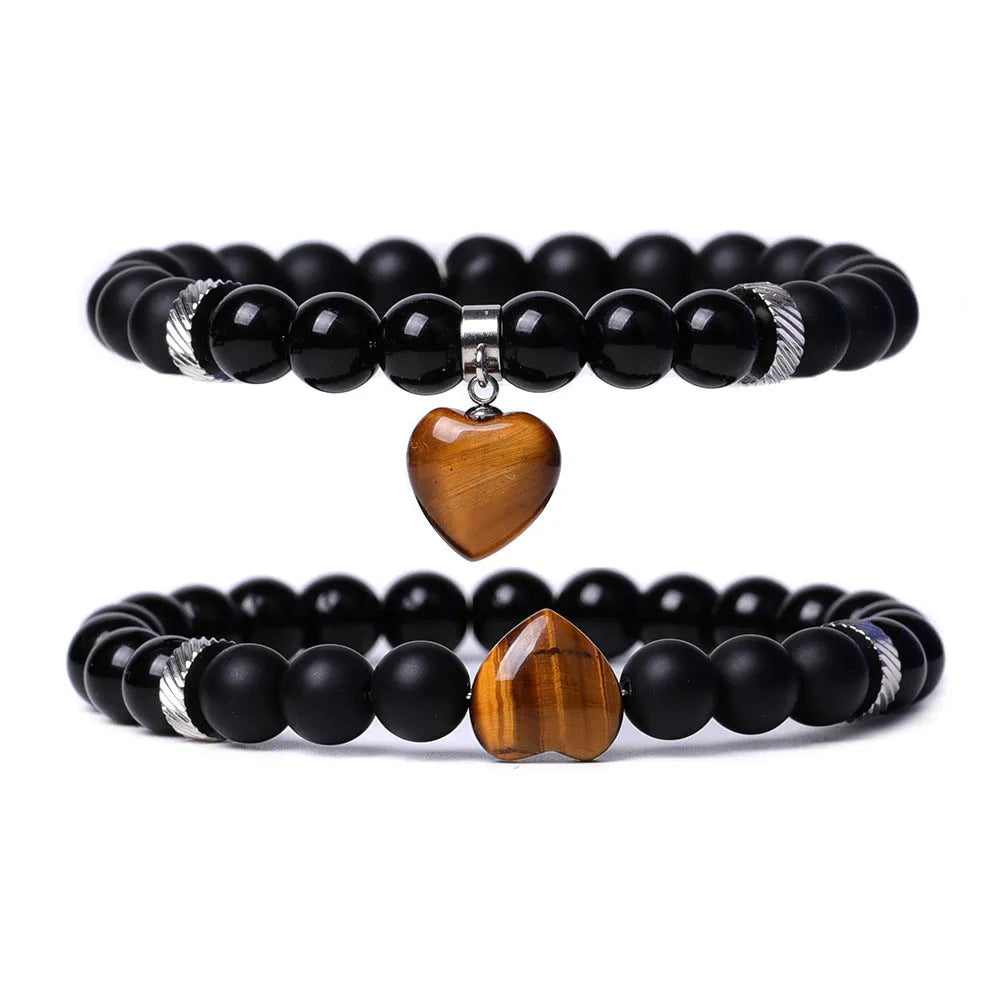 A pair of matching bracelets with polished geometric heart pendants made from natural stone.