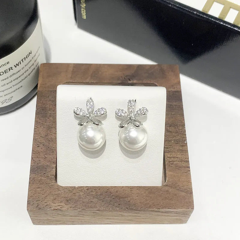 Pair of pearl flower drop earrings in gold and silver finishes on a light background