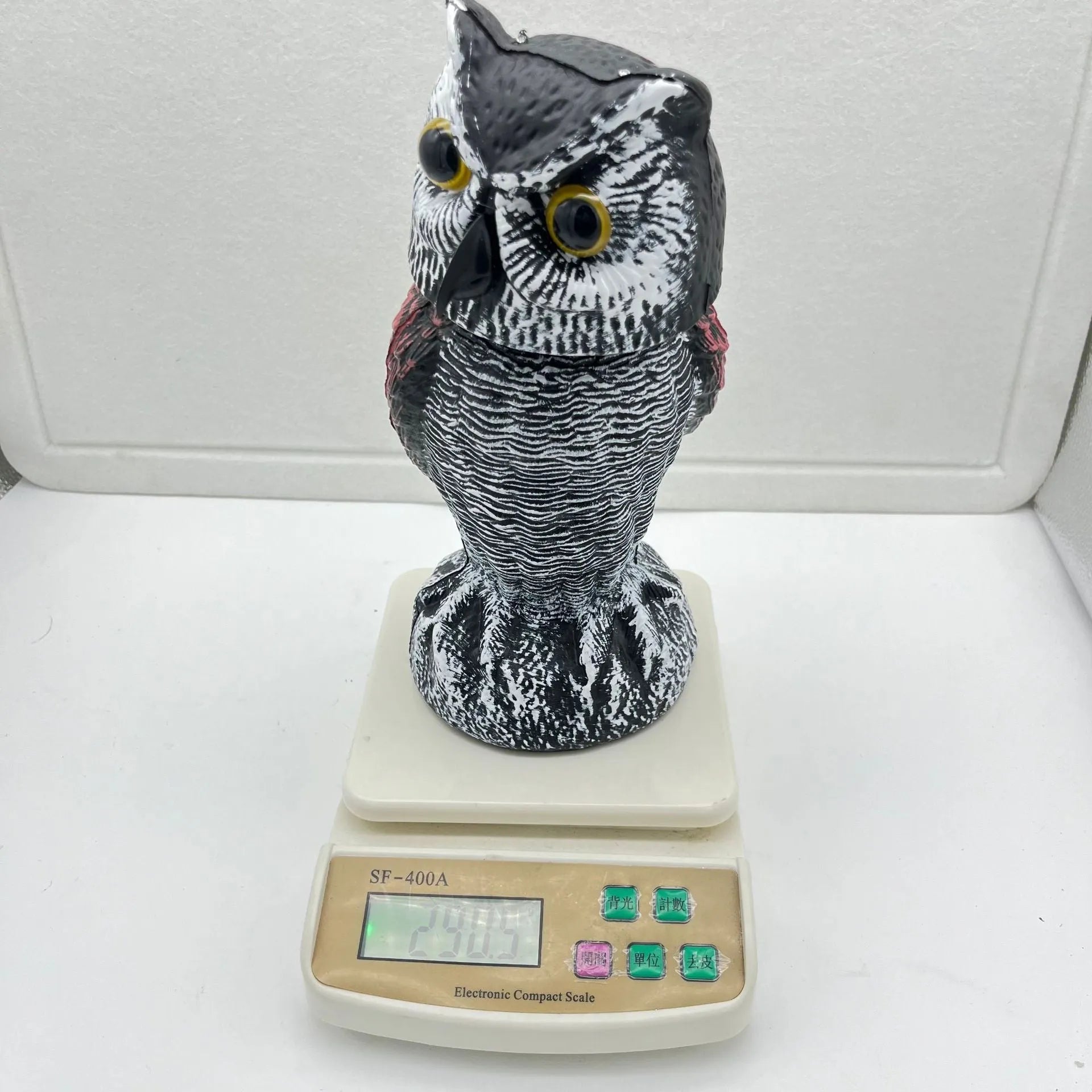 Artificial owl bird scarer decoy with shaking head motion in outdoor setting