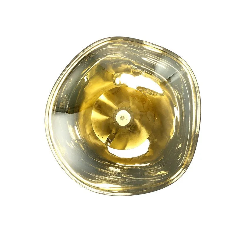 Modern lava wall lamp with acrylic shade in gold finish on a corridor wall emitting warm light