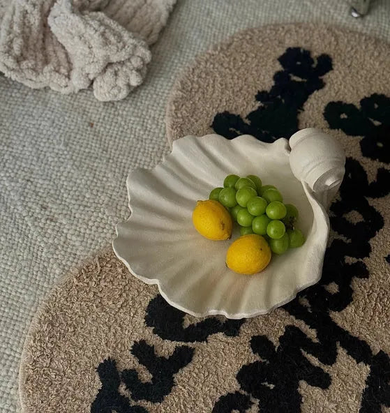 White resin simulation shell fruit plate ornament on a table.