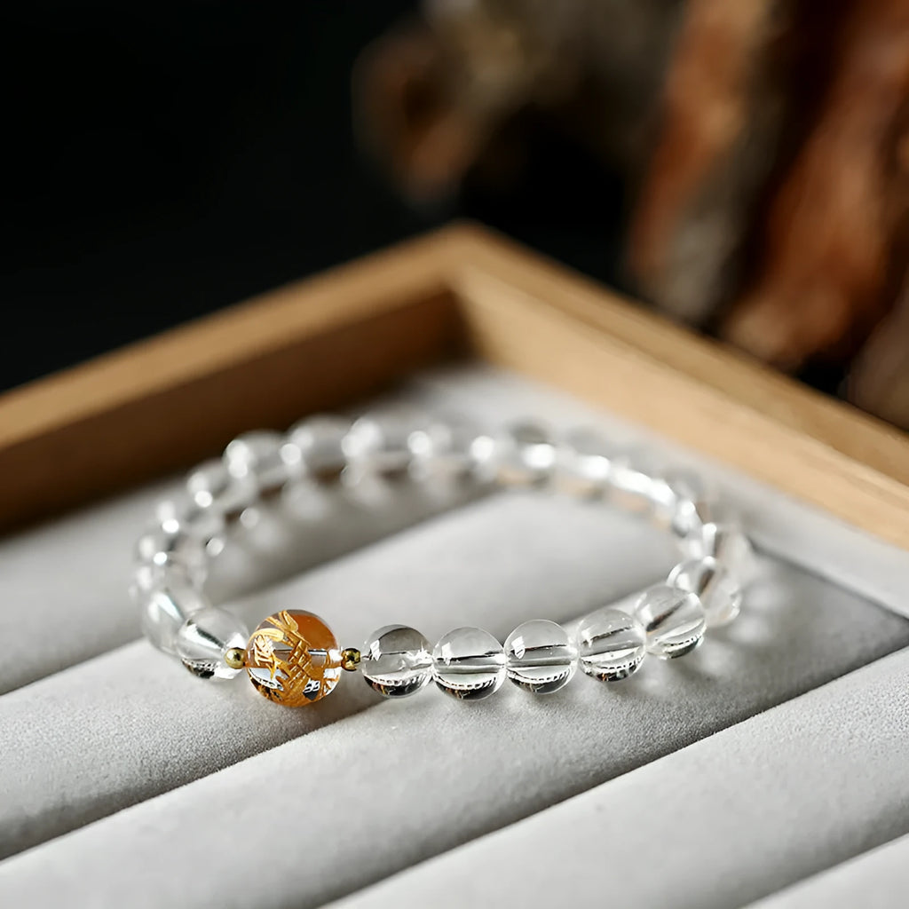 Geometric obsidian and white crystal beaded bracelet with golden dragon charm on a wrist.